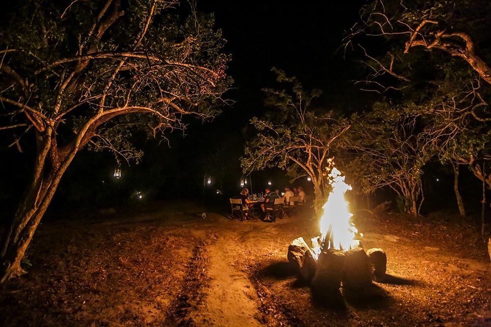 Guests around a bonfire at night at Yala Tented Camp