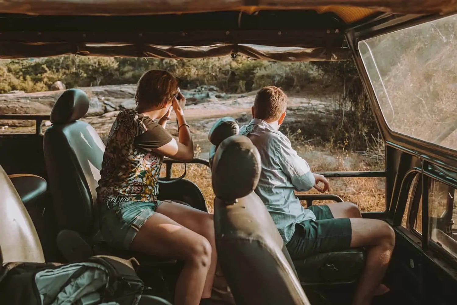 Two guests watching for wildlife from the back of a safari jeep in Yala at golden hour
